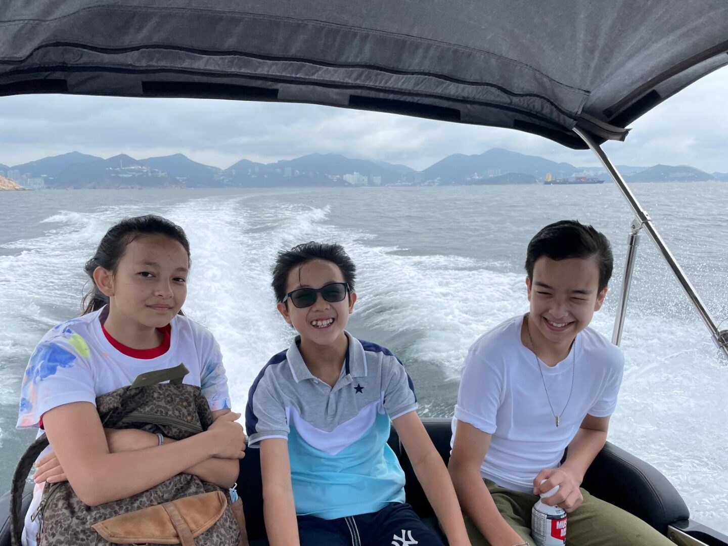 Three young volunteers on a tender boat heading to a remote beach
